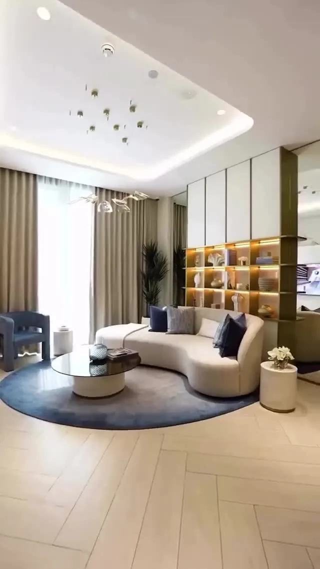 Interior walkthrough still — a luxury living room with curved seating and warm shelf lighting